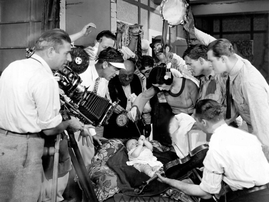 1927. Entertaining a baby on the set of 'The Understanding Heart.'