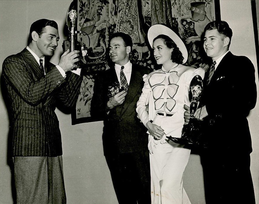 September 20, 1936, on the set of 'Love on the Run.' With Gable and photog Hyman Fink, center.