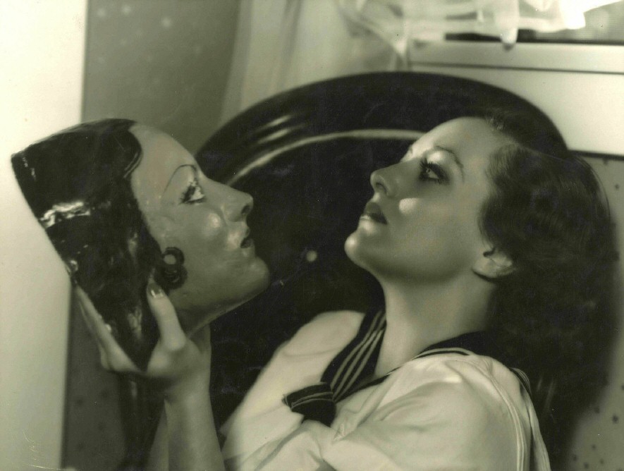 1931. In her dressing room, shot by Hurrell. With mask made by actor Richard Cromwell.