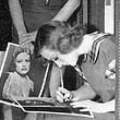 1933. Signing autographs for extras on the set of 'Dancing Lady.'