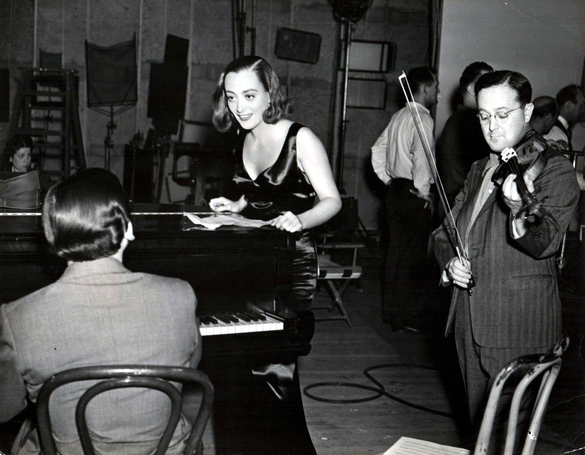 1937. 'Bride Wore Red' set. Composer Franz Waxman on piano.