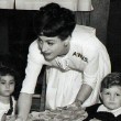 1943. Serving kids lunch at the AWVS daycare center she funded during the war. Includes press caption.