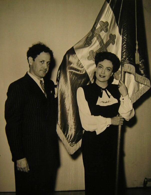 1942. On the set of 'Reunion in France' with Sylvane Robert and the flag of the Free French Republic.