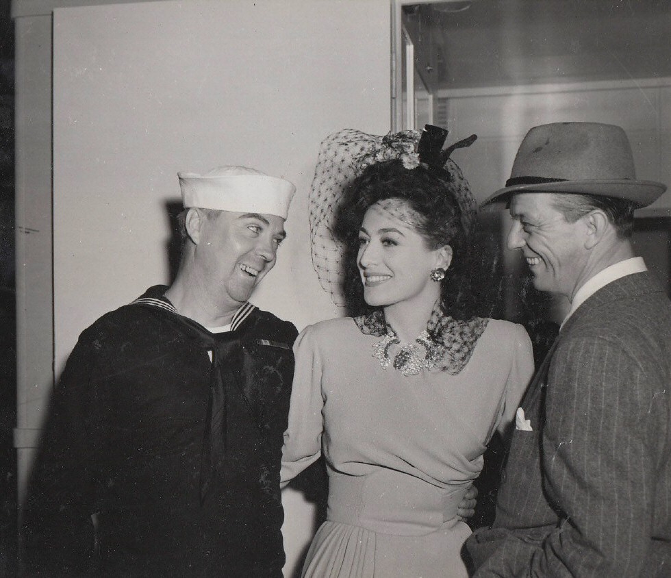 1942. On the set of 'They All Kissed the Bride' with Navy man Eddie Featherstone and director Alexander Hall.