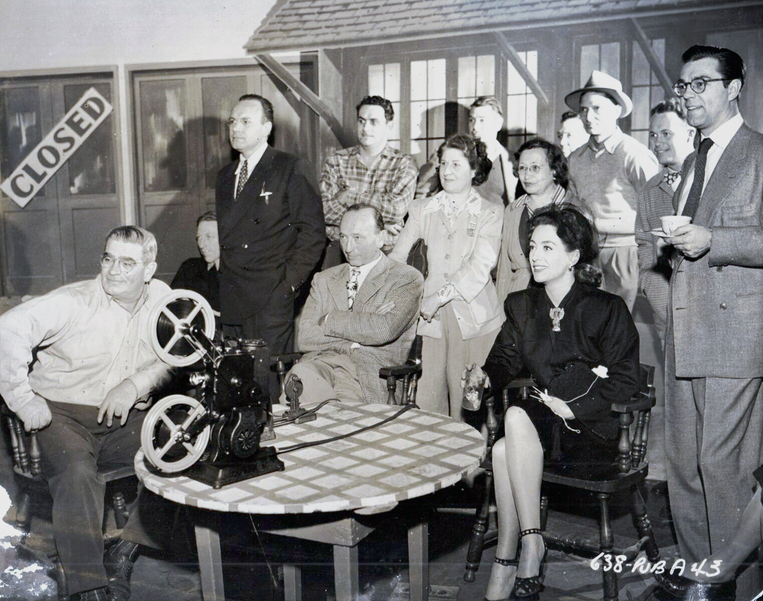 On the set of 'Mildred Pierce' with director Curtiz, crew, and husband Phil Terry.