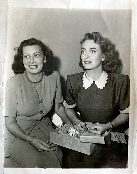 Candid snapshot on the set of 'Daisy Kenyon' with fan club president Edith Clemens.