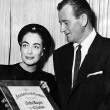 1952. Presenting John Wayne with Interstate Circuit of Theatres award (includes press caption).