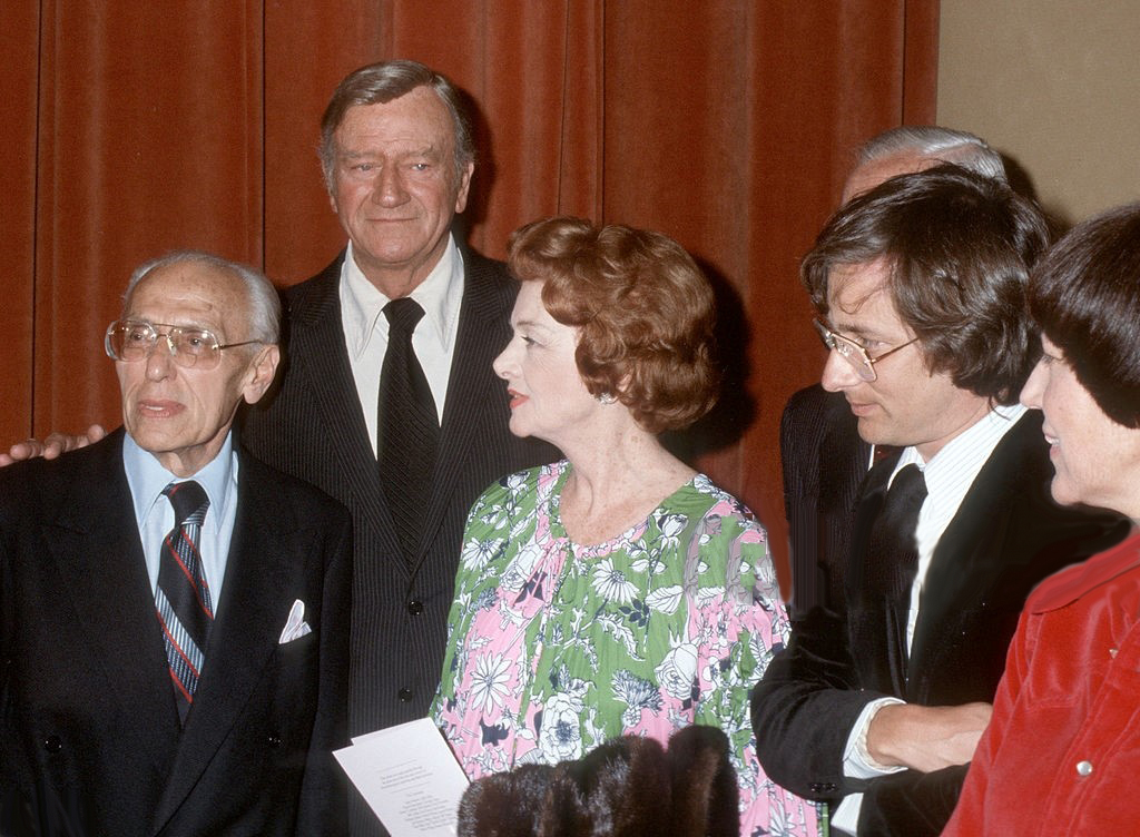 June 24, 1977. At the Samuel Goldwyn Theater tribute to Joan organized by George Cukor. From left: Cukor, John Wayne, Myrna Loy, Steven Spielberg.