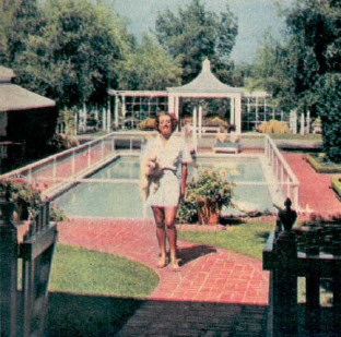 The pool is lined with blue tile, and the fence around it keeps the children out. Building on the left has a shower and dressing room that can serve as guest quarters. 