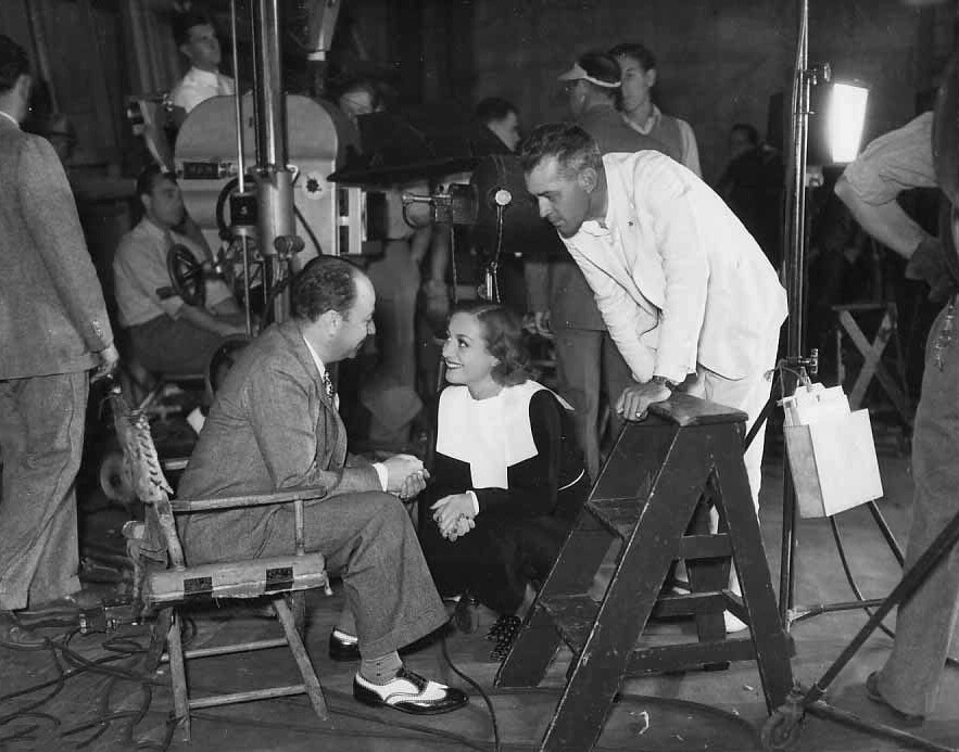 1935. On the set of 'I Live My Life' with producer Bernard Hyman and director W. S. Van Dyke.