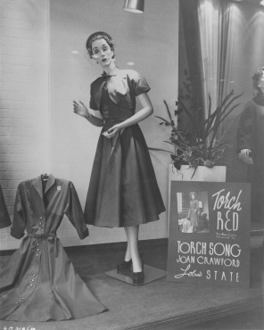 Store window display of a 'Torch Red' dress, tying in with 'Torch Song.'