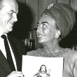 1964. Cartoonist Milton Caniff presents Joan with a 'Dragon Lady' birthday card.